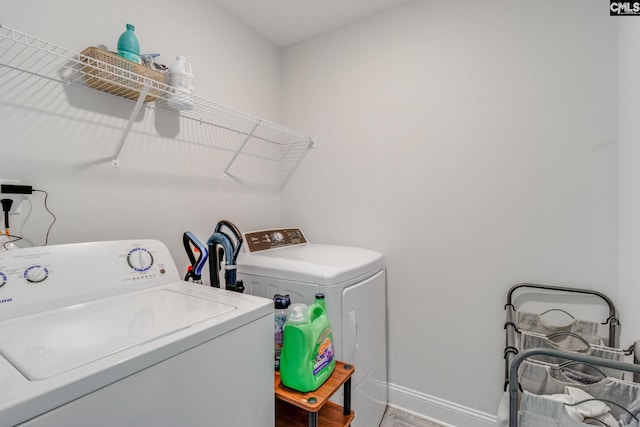 laundry room with baseboards, wood finished floors, laundry area, and washer and clothes dryer