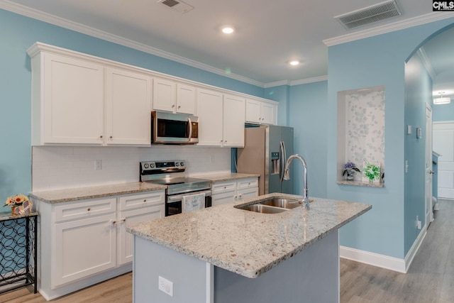 kitchen featuring a center island with sink, visible vents, arched walkways, a sink, and appliances with stainless steel finishes