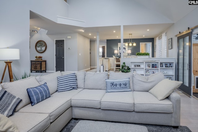 living area featuring wood finished floors, baseboards, a high ceiling, recessed lighting, and a barn door