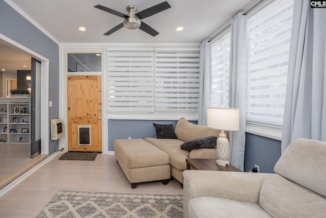 living room with heating unit, wood finished floors, recessed lighting, ceiling fan, and crown molding