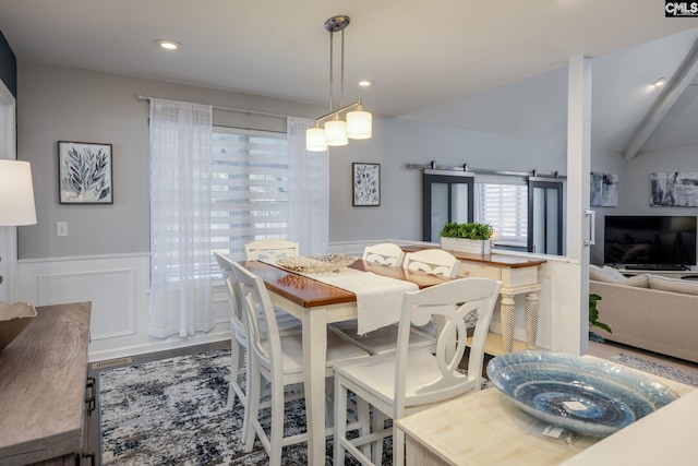 dining space with lofted ceiling, a decorative wall, recessed lighting, and a wainscoted wall