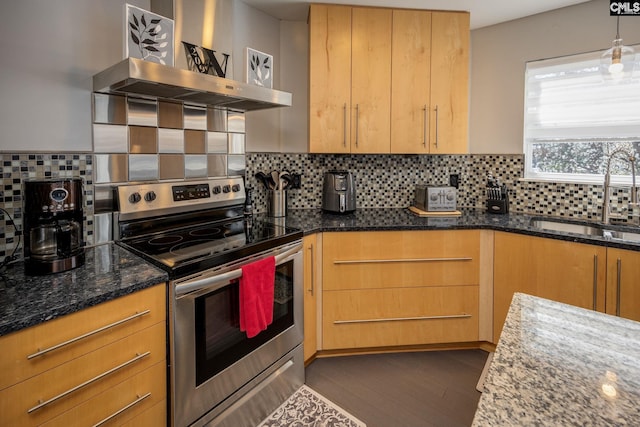 kitchen with dark stone counters, stainless steel electric stove, a sink, wall chimney exhaust hood, and backsplash