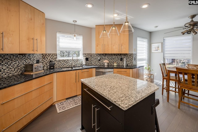 kitchen featuring dark stone counters, ceiling fan, a sink, stainless steel dishwasher, and tasteful backsplash