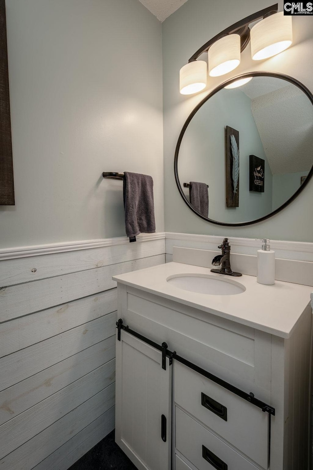 bathroom with vanity, wood walls, and wainscoting