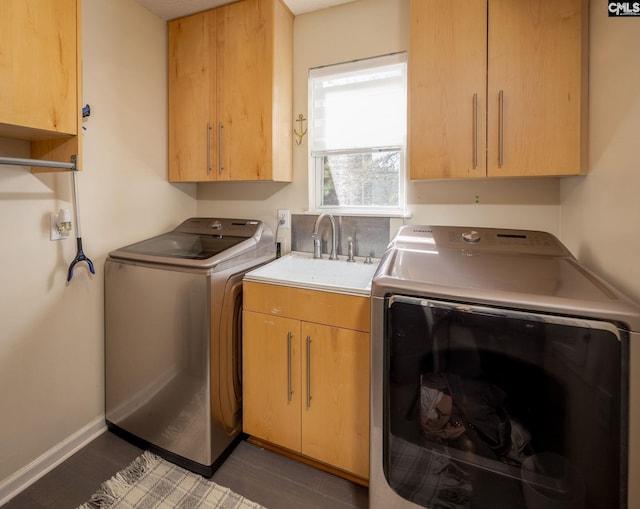 laundry room with a sink, cabinet space, baseboards, dark wood-style flooring, and washing machine and clothes dryer