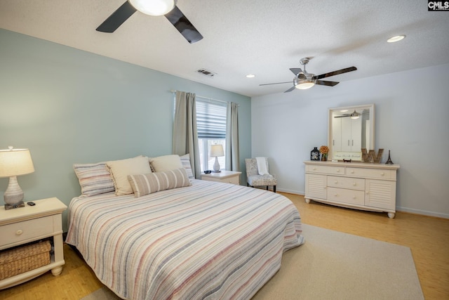 bedroom featuring a textured ceiling, baseboards, visible vents, and light wood-type flooring