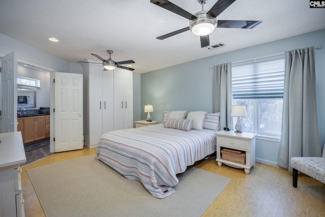 bedroom with a closet, visible vents, light wood-style flooring, and a textured ceiling