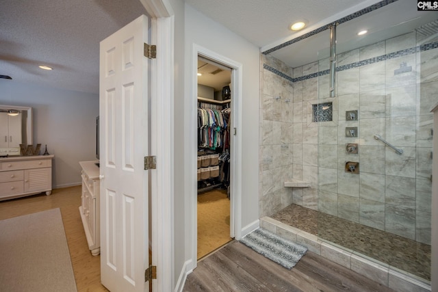 full bathroom with a stall shower, vanity, a textured ceiling, and wood finished floors