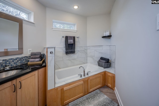 bathroom featuring decorative backsplash, vanity, a garden tub, and wood finished floors