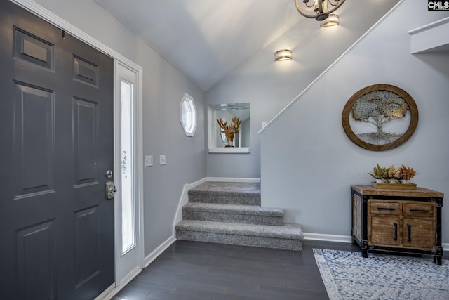 foyer entrance with stairway, dark wood-style flooring, baseboards, and vaulted ceiling