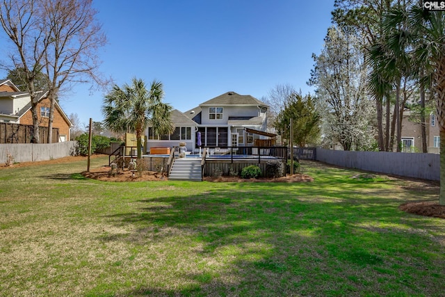 back of house featuring a lawn, a wooden deck, and a fenced backyard