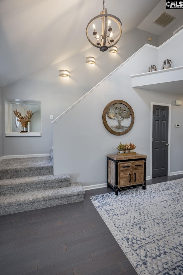 stairway featuring wood finished floors, visible vents, baseboards, high vaulted ceiling, and a notable chandelier