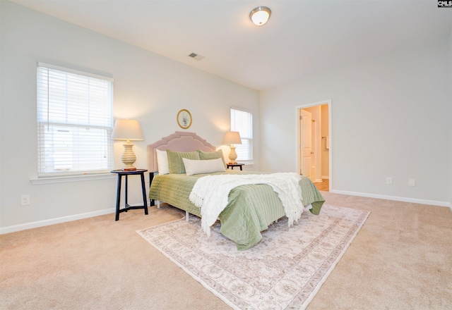 carpeted bedroom with visible vents, ensuite bathroom, and baseboards