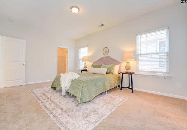 bedroom featuring a spacious closet, light colored carpet, visible vents, and baseboards