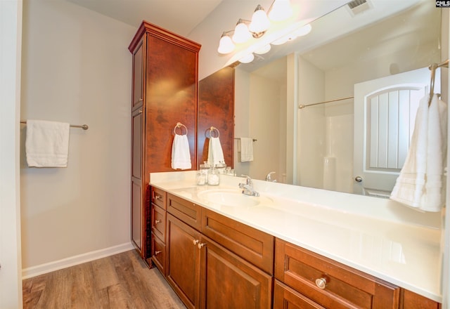 bathroom with visible vents, walk in shower, baseboards, wood finished floors, and vanity