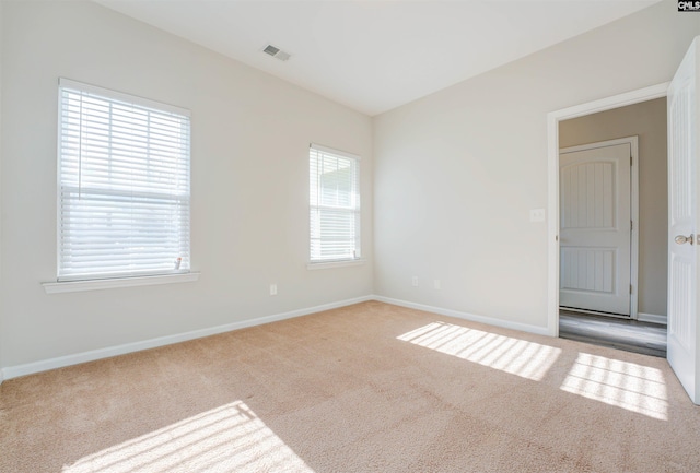 empty room featuring visible vents, carpet floors, and baseboards