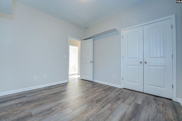 unfurnished bedroom with a closet, baseboards, and wood finished floors