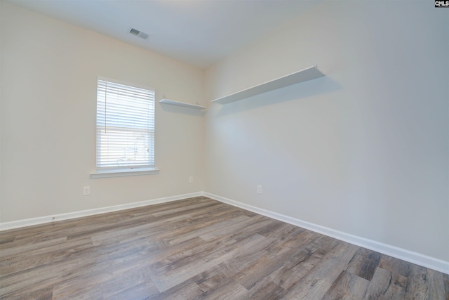 spare room featuring visible vents, baseboards, and wood finished floors