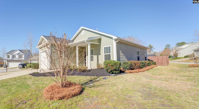 view of front of home with a front yard, concrete driveway, fence, and a garage