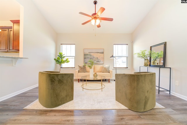 sitting room with vaulted ceiling, wood finished floors, a ceiling fan, and baseboards