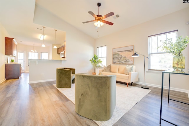 living area featuring visible vents, a ceiling fan, light wood-type flooring, and baseboards