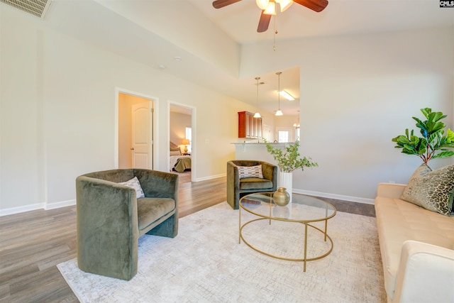 living room featuring visible vents, baseboards, ceiling fan, vaulted ceiling, and wood finished floors