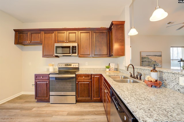 kitchen featuring a sink, stainless steel appliances, light stone counters, and light wood finished floors