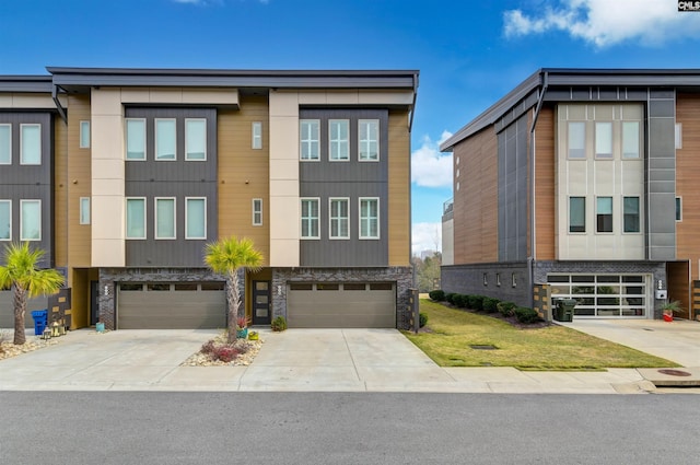 contemporary home with an attached garage, stone siding, and driveway