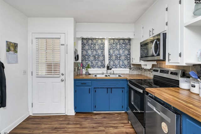 kitchen with dark wood-style floors, blue cabinetry, a sink, stainless steel appliances, and wood counters