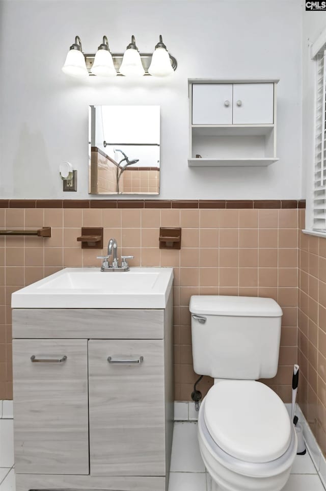 bathroom with toilet, tile walls, vanity, and tile patterned flooring