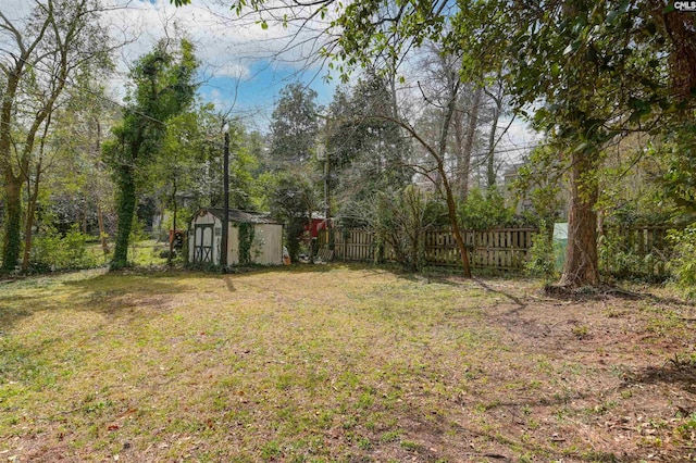 view of yard with an outbuilding, fence, and a shed