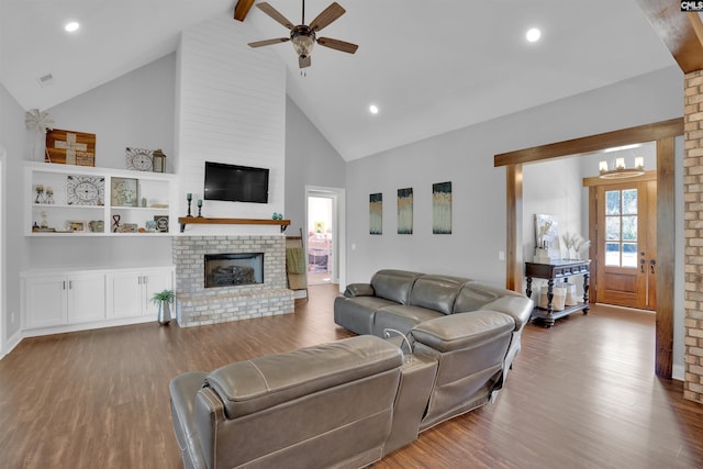 living area featuring wood finished floors, a brick fireplace, and a ceiling fan