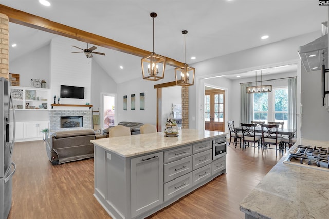 kitchen featuring ceiling fan with notable chandelier, a fireplace, stainless steel appliances, and wood finished floors