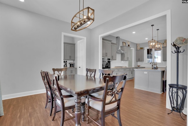 dining area featuring light wood-type flooring, baseboards, and a notable chandelier