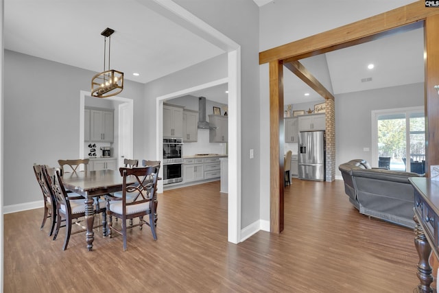 dining area with light wood finished floors, a chandelier, visible vents, and baseboards