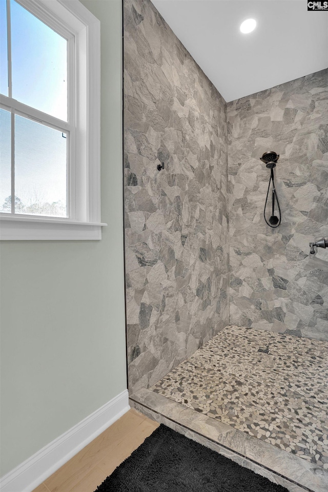 bathroom with a tile shower, baseboards, and wood finished floors