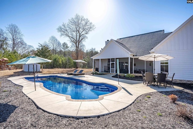 outdoor pool with a patio area, a storage shed, an outbuilding, and a sunroom