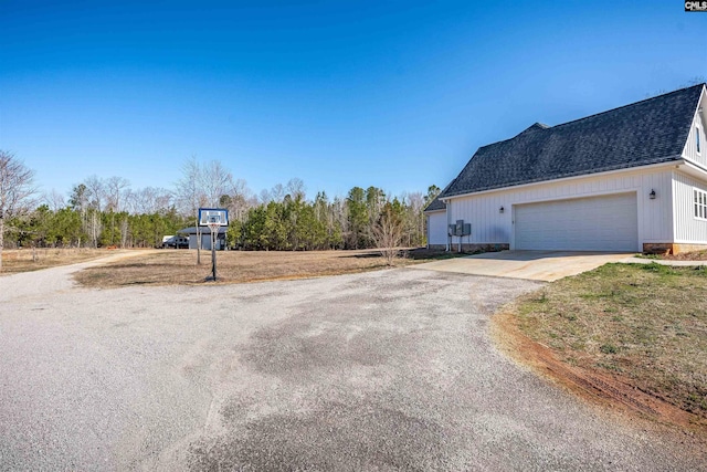 view of side of property with an attached garage, concrete driveway, and a shingled roof