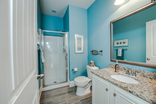 bathroom with vanity, wood tiled floor, a shower stall, and toilet