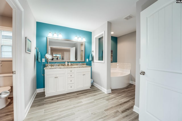 full bathroom with a bath, visible vents, wood tiled floor, double vanity, and toilet