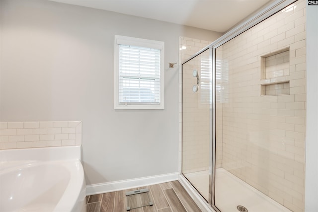 bathroom featuring a bath, baseboards, a stall shower, and wood tiled floor