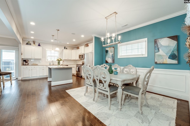 dining room featuring wainscoting, dark wood-style flooring, and crown molding