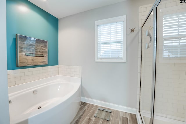 bathroom featuring wood finish floors, baseboards, a stall shower, and a bath