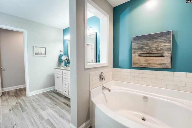 bathroom featuring vanity, a garden tub, wood finished floors, and baseboards