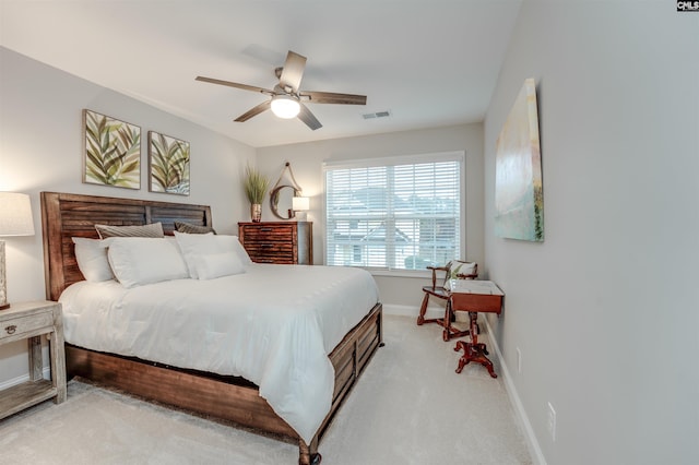 bedroom with visible vents, baseboards, light colored carpet, and a ceiling fan