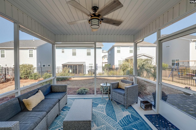 sunroom featuring a residential view, a healthy amount of sunlight, and a ceiling fan