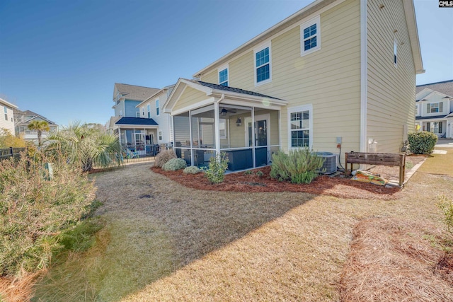 rear view of house with a lawn, a ceiling fan, fence, cooling unit, and a sunroom