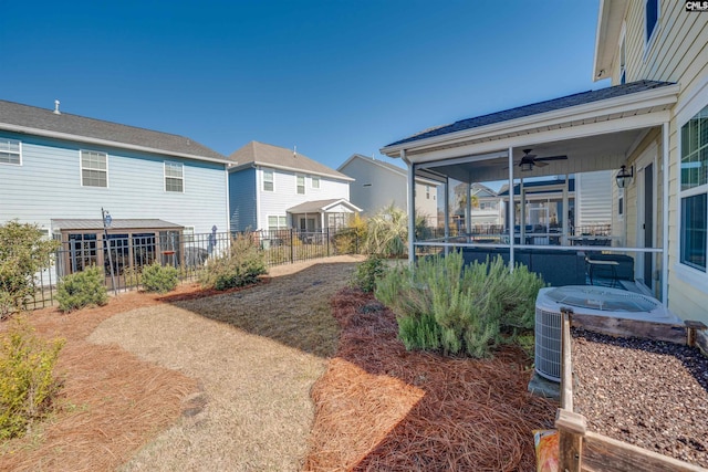 view of yard featuring central air condition unit, a sunroom, a ceiling fan, and fence