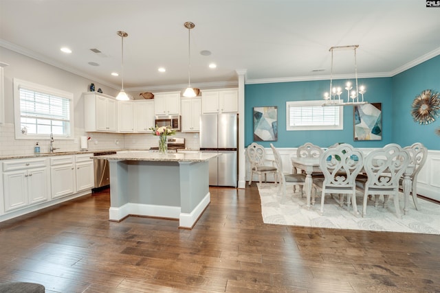 kitchen with visible vents, a sink, stainless steel appliances, dark wood-type flooring, and a center island