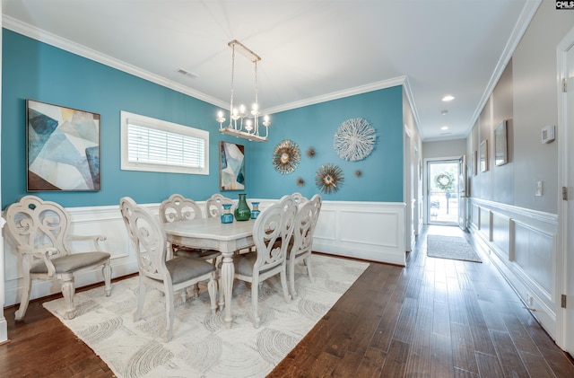 dining area with visible vents, crown molding, a chandelier, a wainscoted wall, and wood finished floors